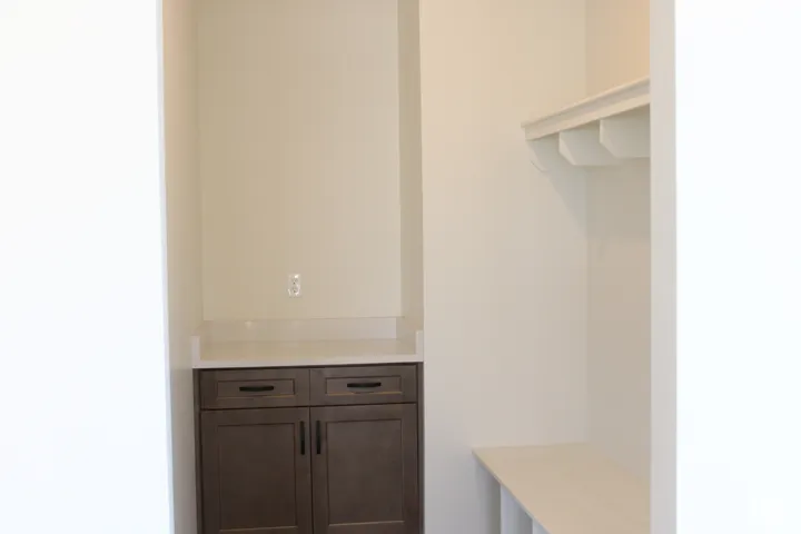 Built-in storage cabinetry with dark finish, white countertop, and integrated bench seating with overhead shelving