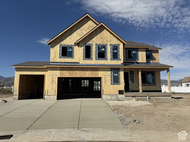 Two-story residence featuring a covered front porch with column supports, multi-pane windows, and a two-car garage with a concrete driveway