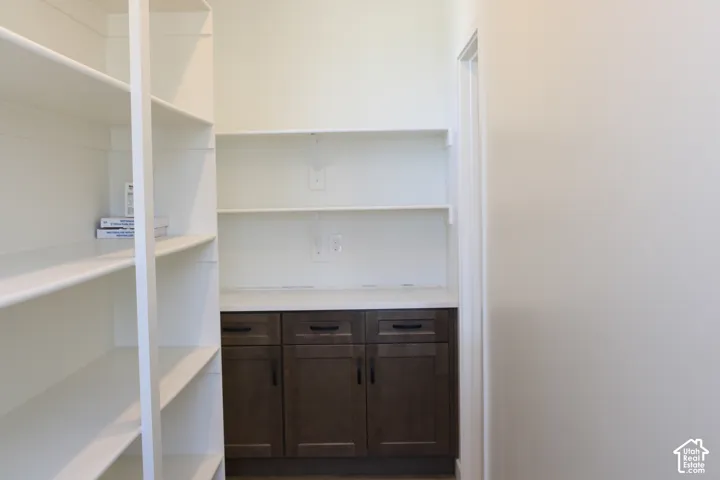 Built-in shelving, white countertops, and dark wood-finish cabinetry with black hardware