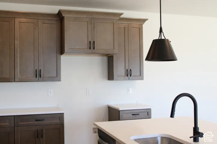 Two-tone cabinetry with dark hardware, solid surface countertops, and a black gooseneck faucet