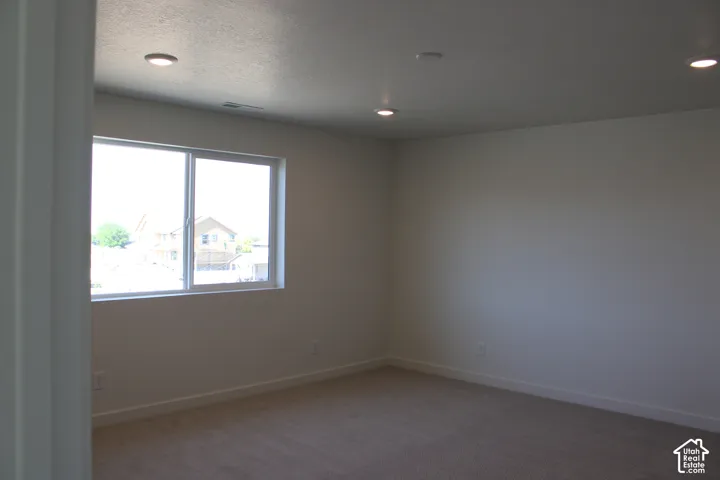 Recessed lighting, wall-to-wall carpeting, and a large window with white trim