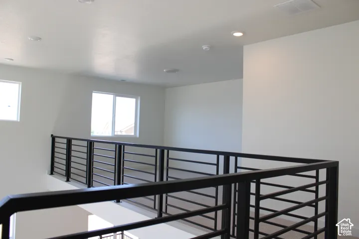 Open loft area featuring a contemporary metal railing, recessed lighting, and multiple windows