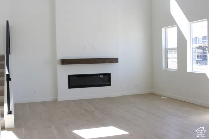 Bright interior with light wood-finish flooring, a linear electric fireplace, and a wood mantel