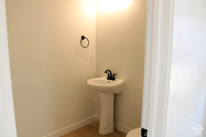 Pedestal sink with a matte black faucet and coordinating towel ring, illuminated by an overhead light fixture