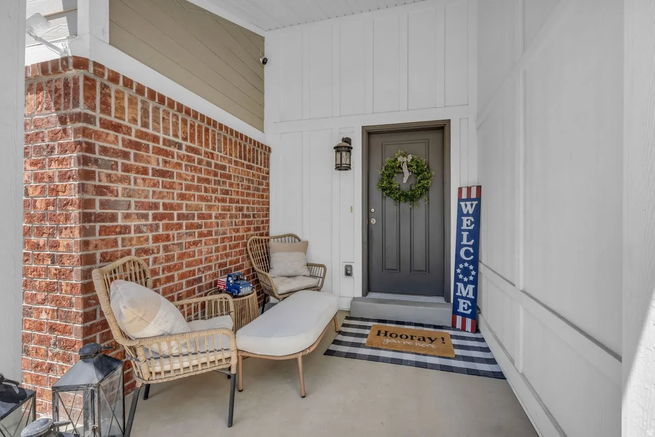 Entryway featuring a dark gray paneled door, brick accent wall, and white siding