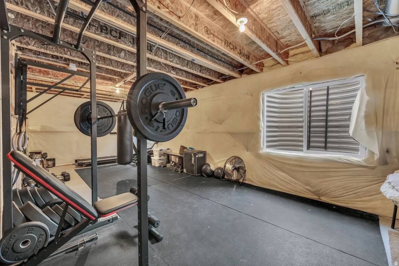 Basement space featuring exposed ceiling joists, a single window, and durable rubber flooring