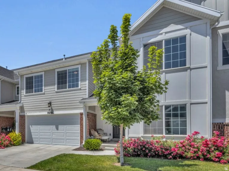 Townhome exterior featuring gray siding, white trim, brick accents, and attached garages