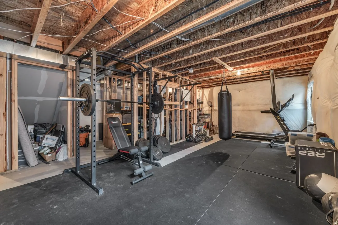 Unfinished lower level featuring exposed ceiling joists, framing for walls, and rubber flooring