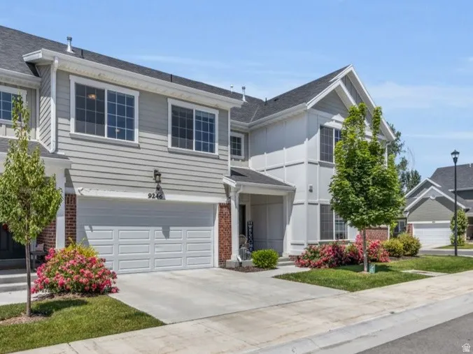 Gray siding exterior with white trim, attached two-car garage, concrete driveway, and front entryway
