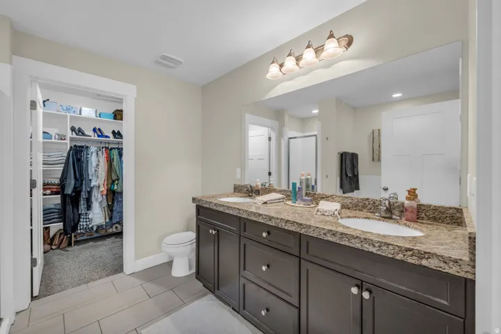 Dual vanity with integrated sinks, dark wood-finish cabinetry, and a speckled countertop