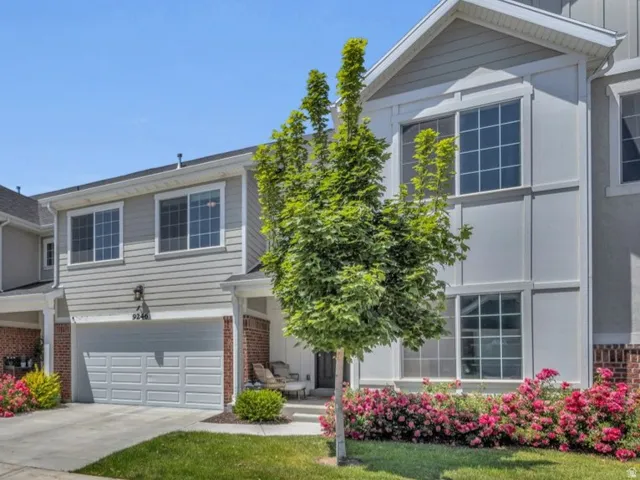 Townhome exterior featuring gray siding, white trim, brick accents, and attached garages