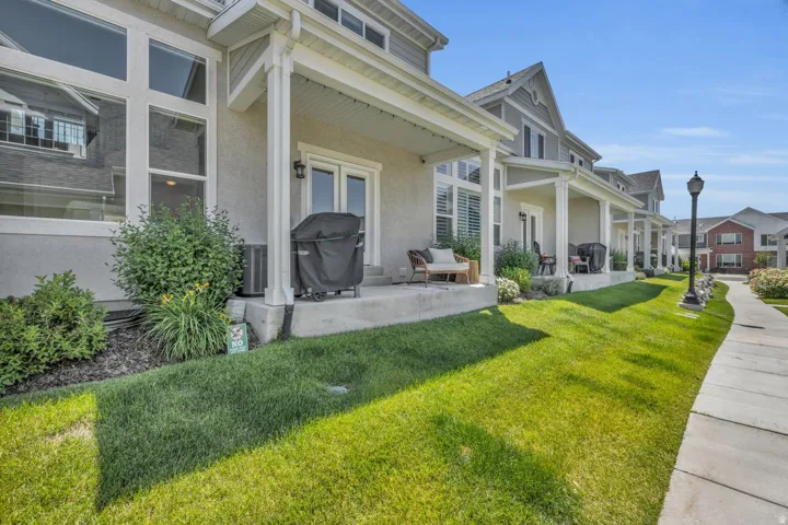 Exterior featuring a covered patio, double glass doors, a concrete walkway, and landscaped garden beds