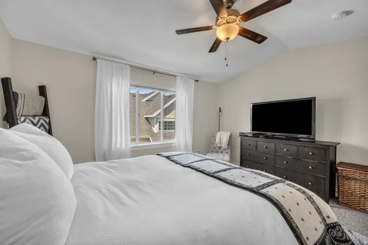 Vaulted ceiling with a ceiling fan light fixture, light-colored walls, and a window with white trim