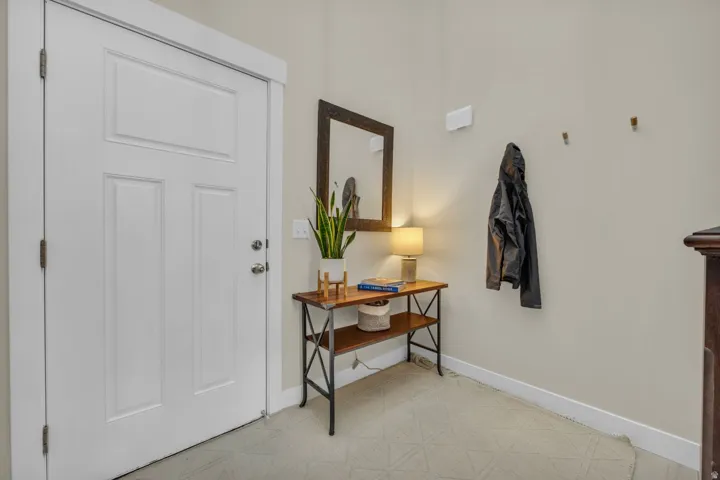 White paneled door with brushed nickel hardware, neutral wall color, and light-toned flooring