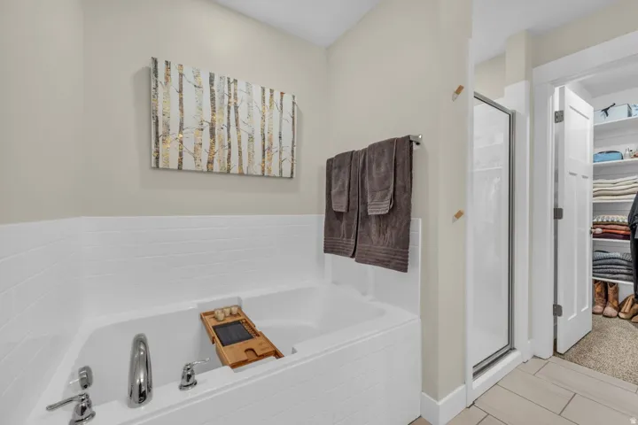 Soaking tub with white subway tile surround, polished chrome fixtures, and a glass-enclosed shower