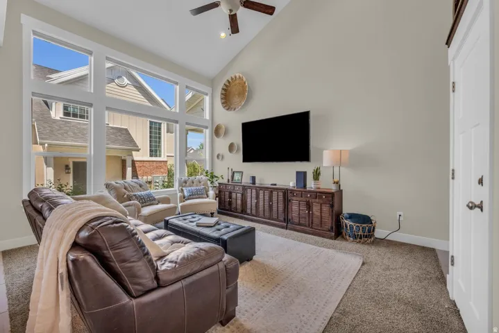 Living area featuring vaulted ceilings, a ceiling fan, and large picture windows