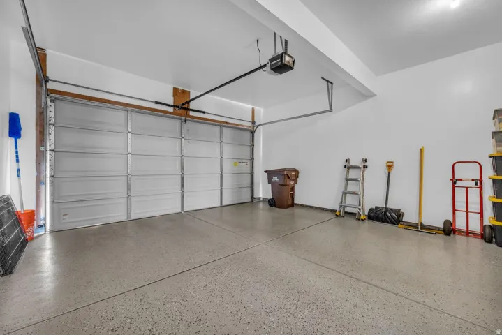 Two-car garage featuring a gray epoxy floor coating, white walls, and an automatic garage door opener