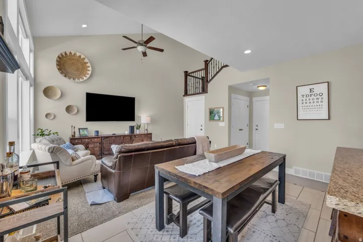 Vaulted ceiling with a ceiling fan, recessed lighting, wood-finish console, and a staircase with wood newel posts and railings