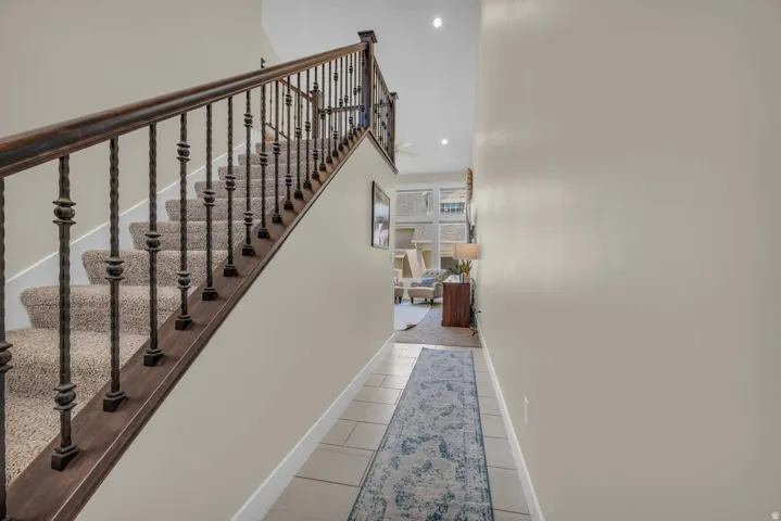 Staircase featuring wrought iron balusters and a wood-finish handrail, with carpeted treads