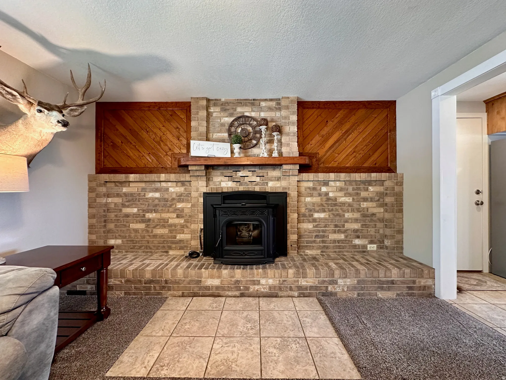 Brick fireplace with a black wood-burning insert and a wood mantel