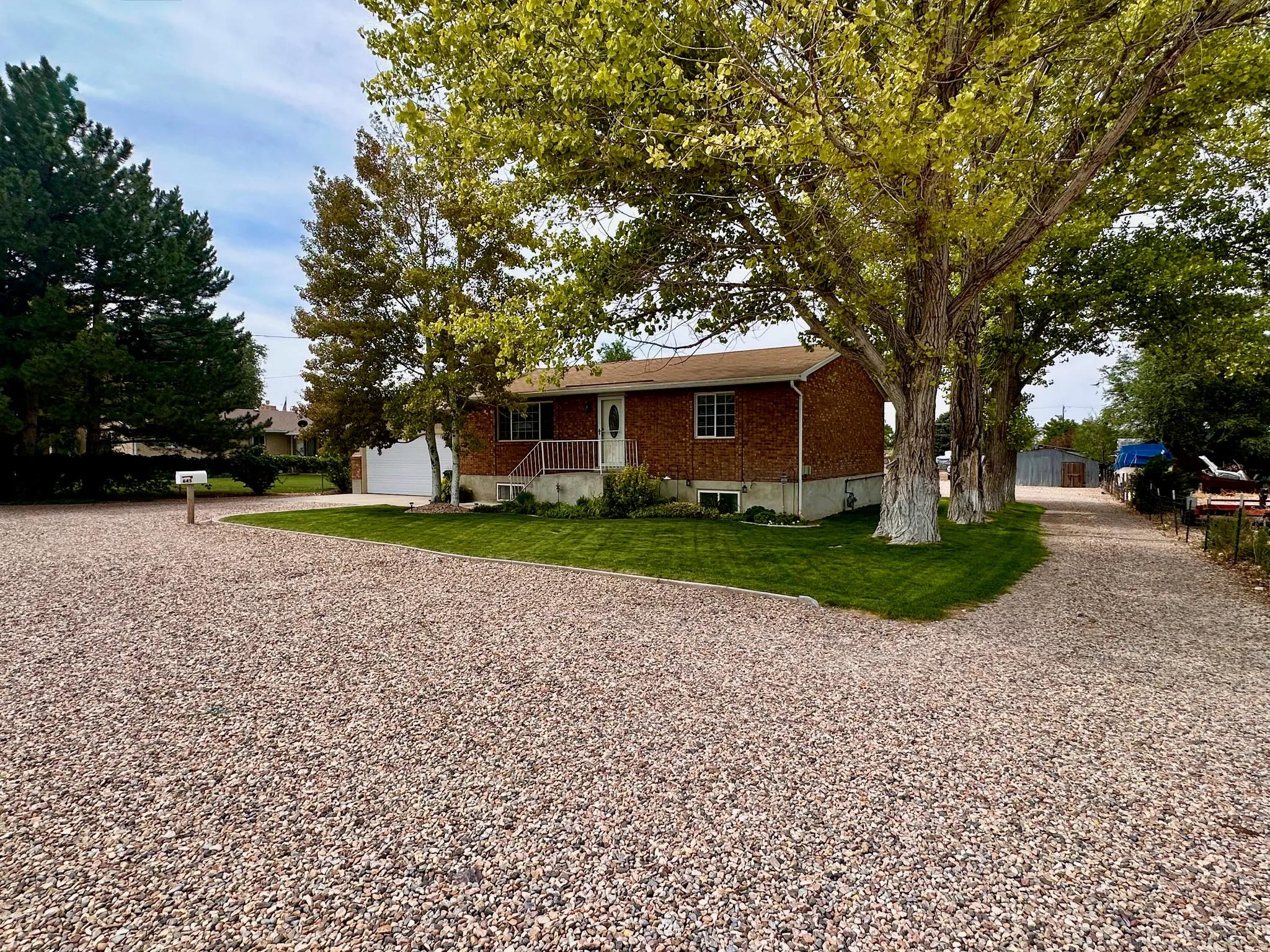 Brick exterior with white trim, a covered porch, and a gravel driveway