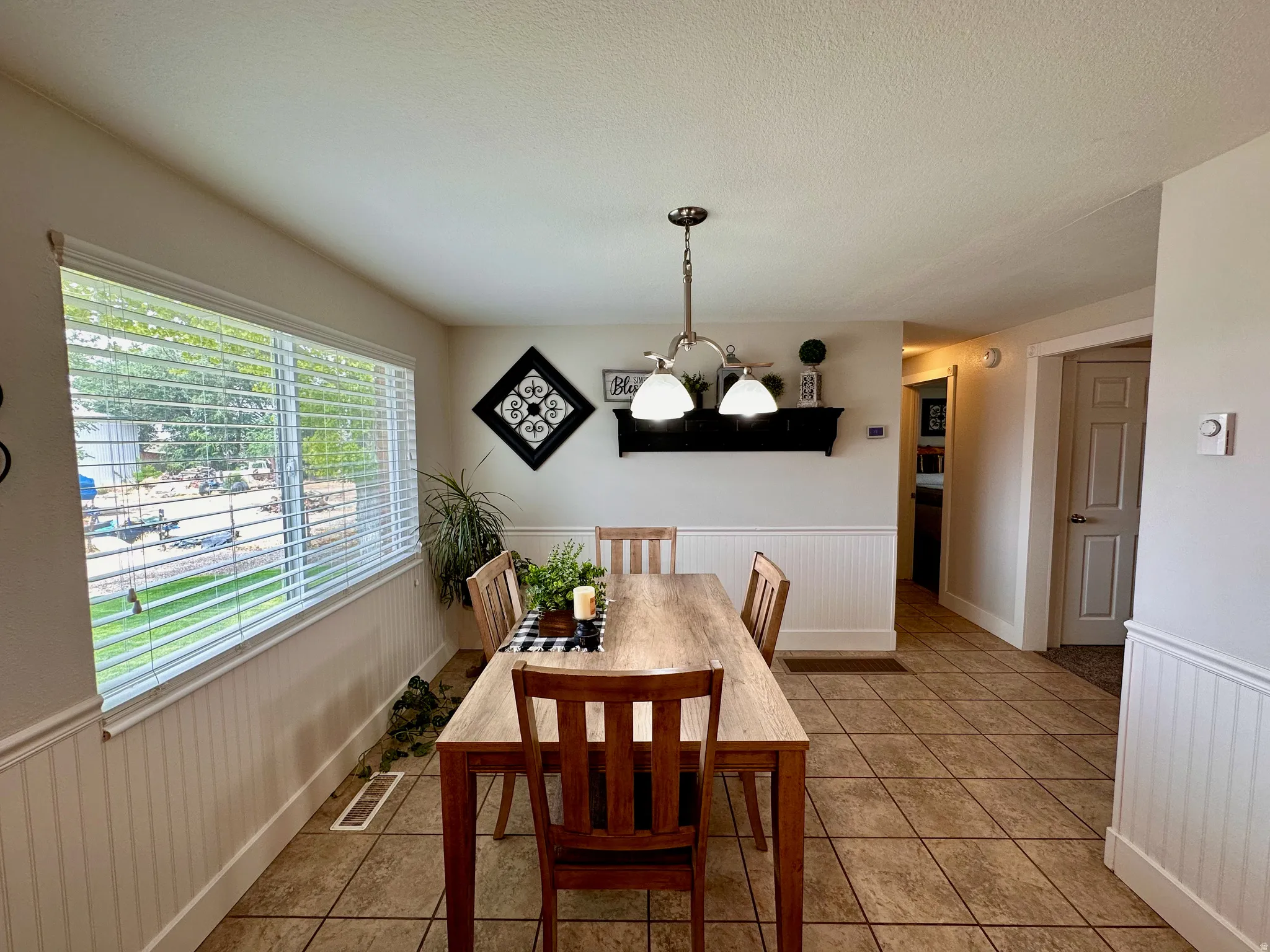 Ceramic tile flooring, white beadboard wainscoting, and a multi-pane window with blinds