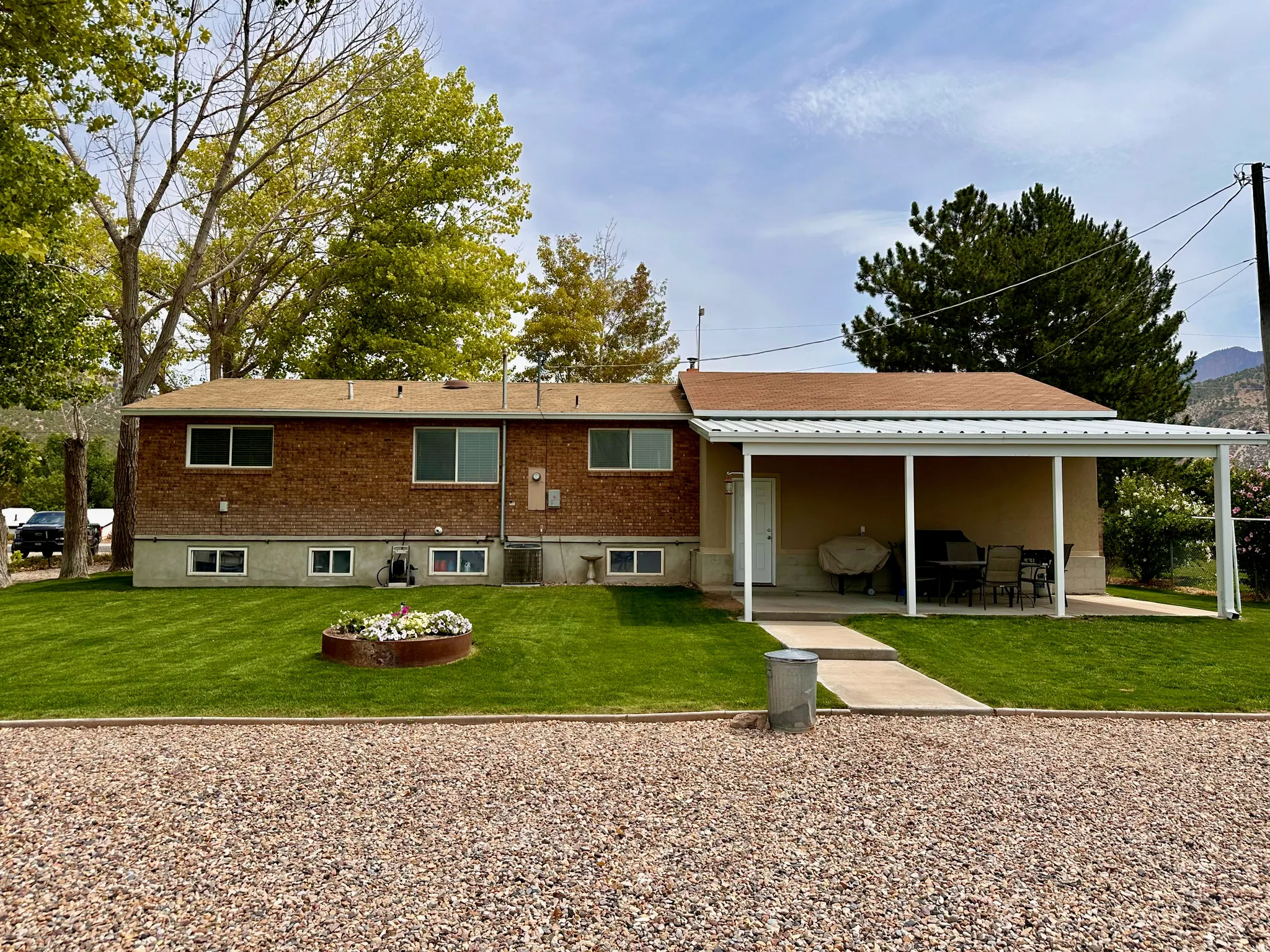 Expansive gravel parking area, manicured lawn, and a covered patio structure