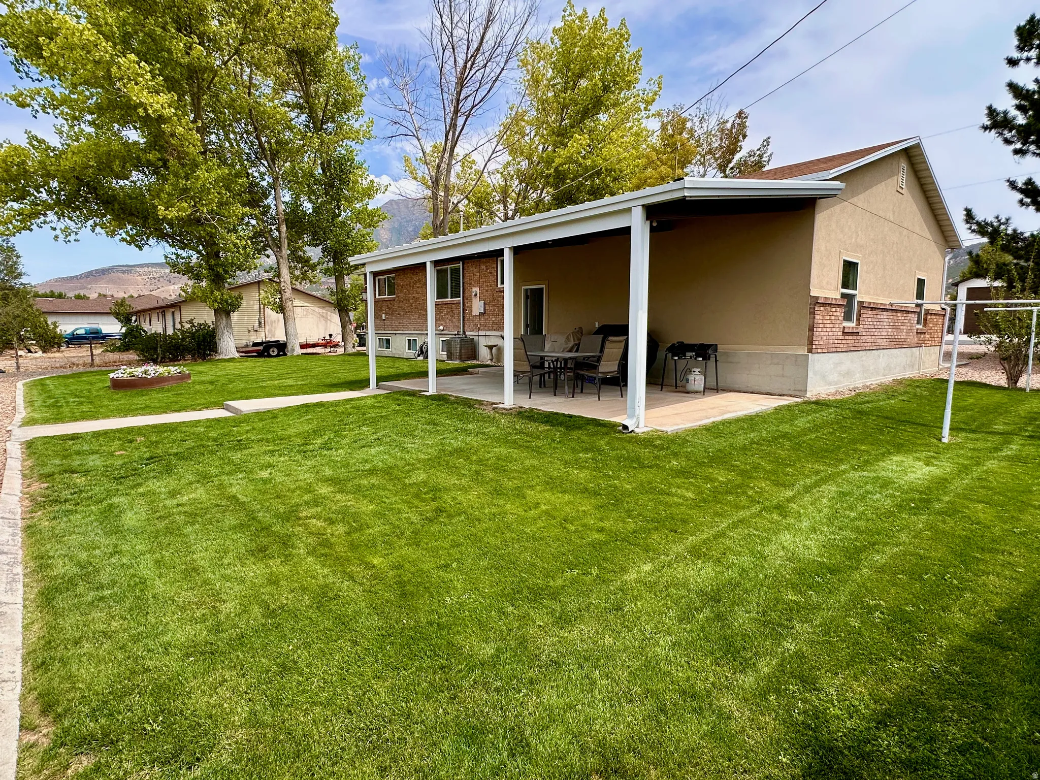 Covered patio with a concrete surface, brick and stucco exterior, and a spacious lawn