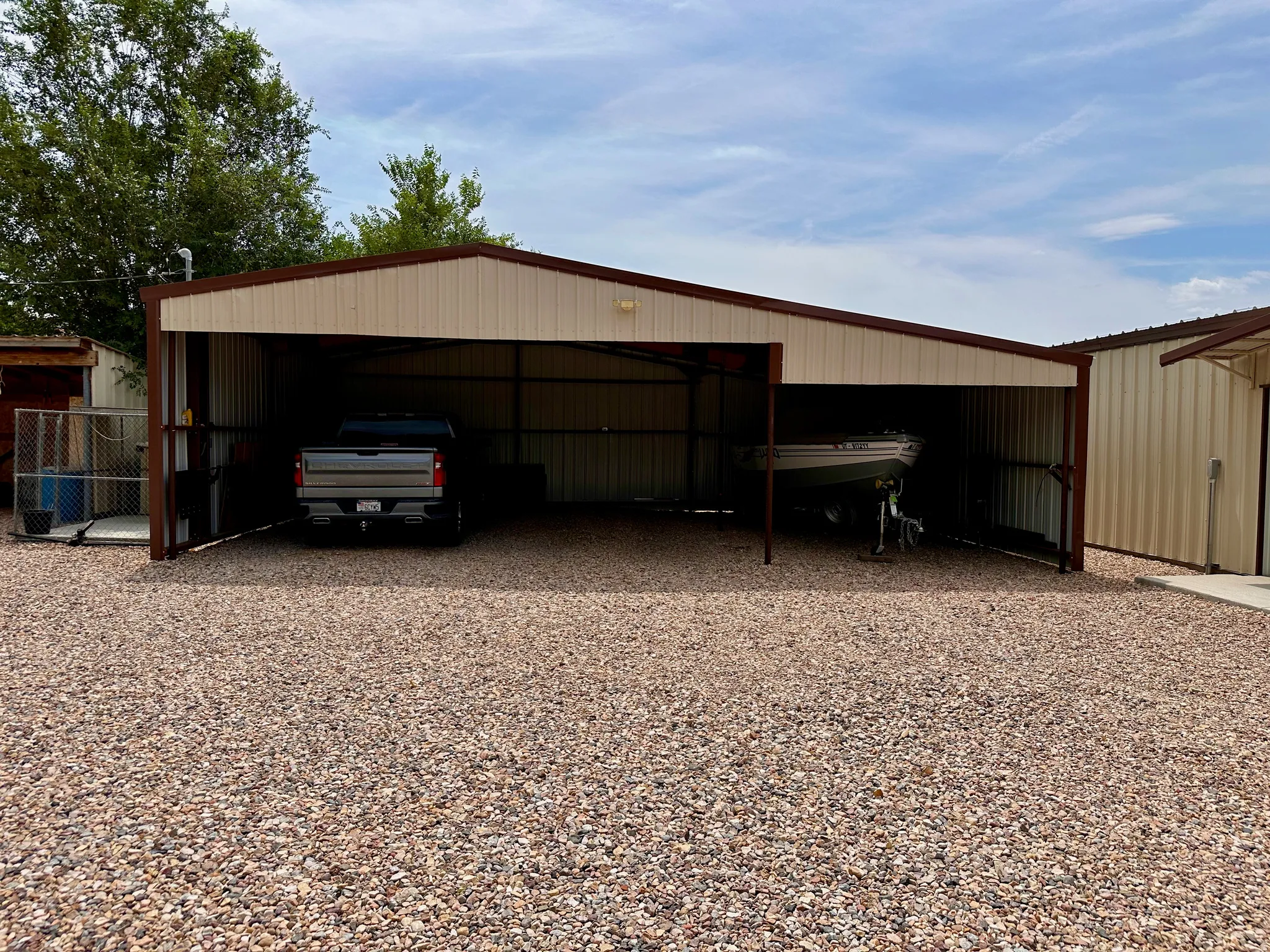 Metal carport structure with a gabled roof, supporting posts, and metal siding