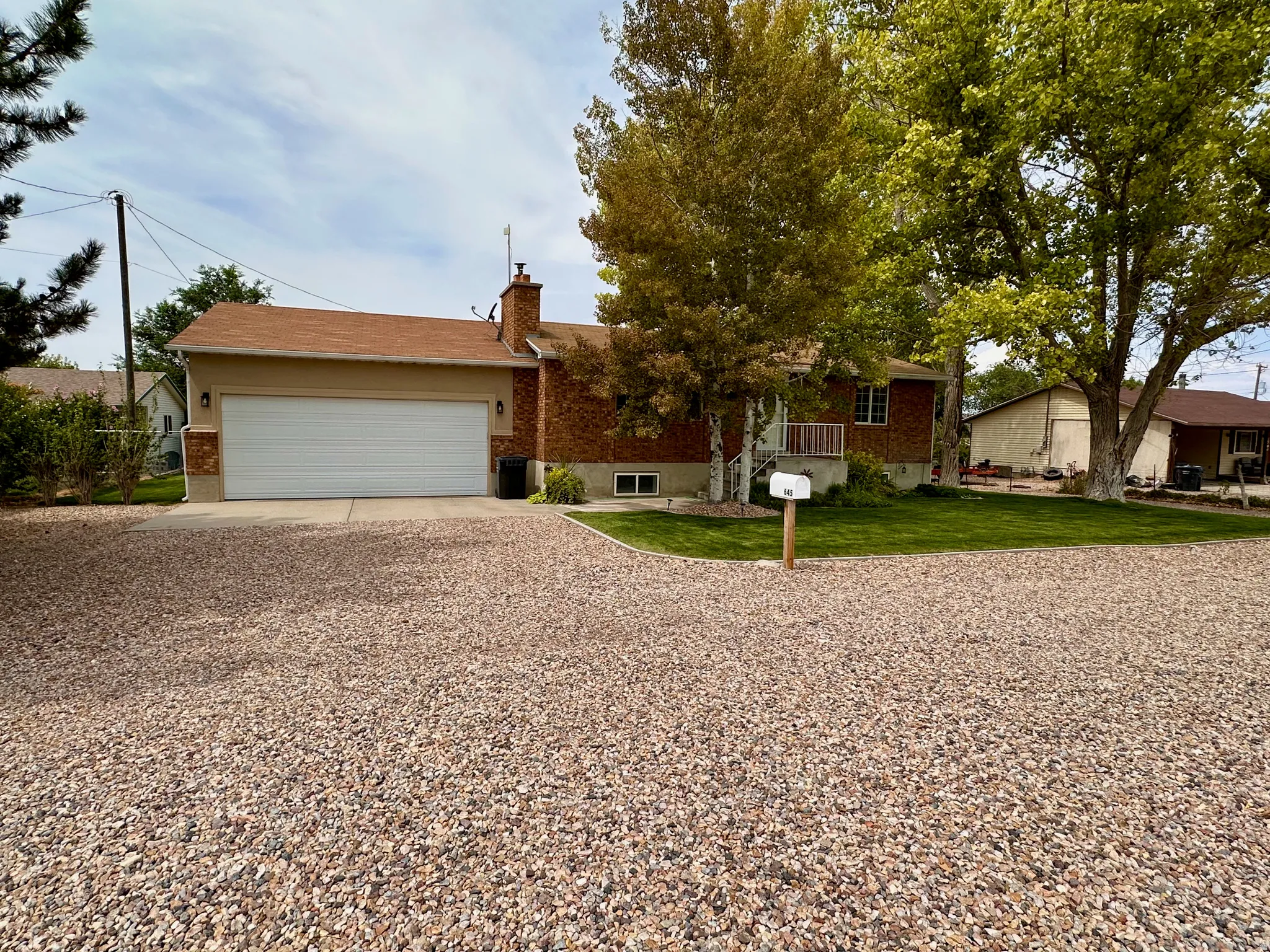 Brick exterior with light stucco accents, a two-car garage, and a gravel driveway