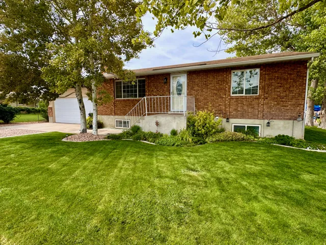 Brick exterior featuring an attached two-car garage, front entry with white railing, and established landscaping