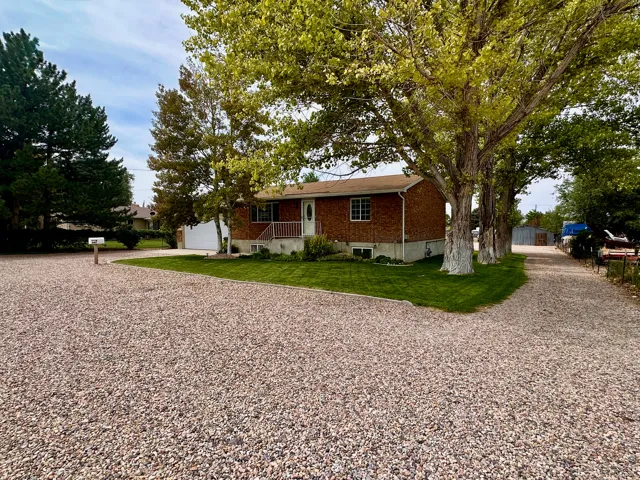 Brick exterior with white trim, a covered porch, and a gravel driveway