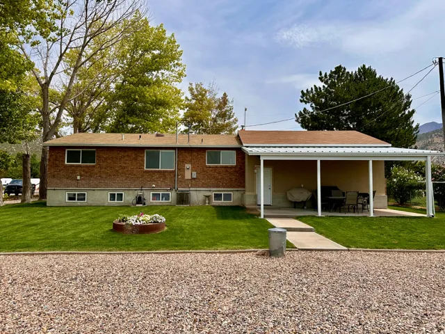Expansive gravel parking area, manicured lawn, and a covered patio structure
