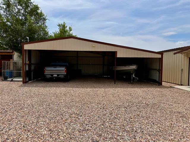 Metal carport structure with a gabled roof, supporting posts, and metal siding