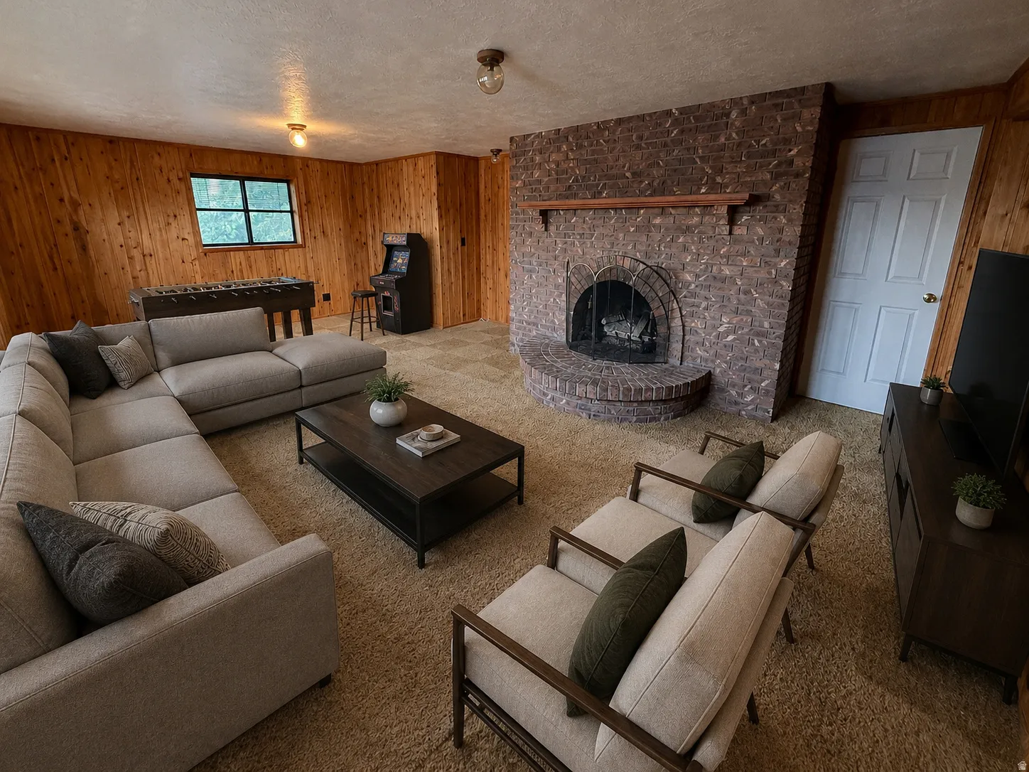 Brick fireplace with hearth, wood paneling, and a window