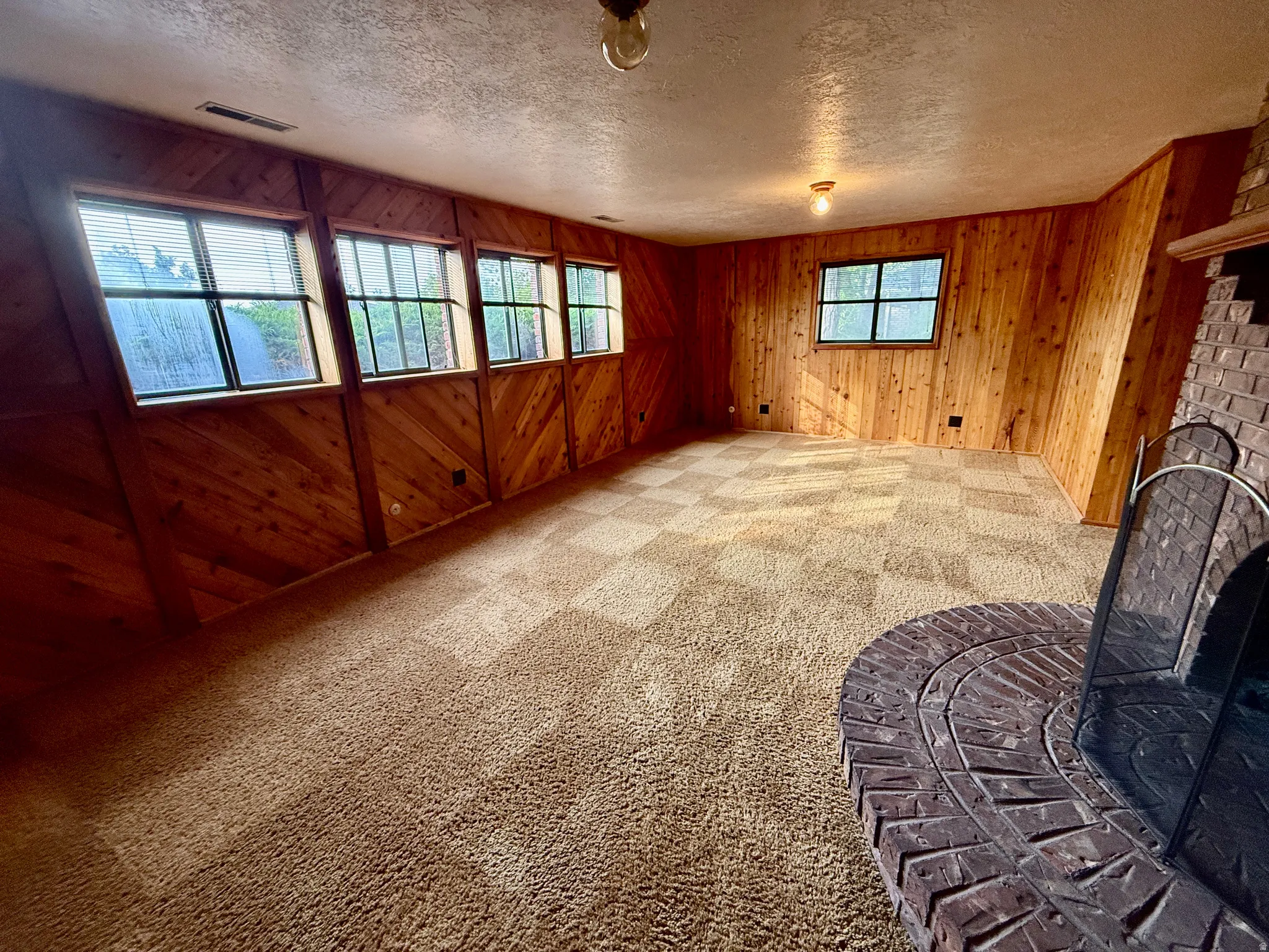 Wood-paneled room featuring multiple windows, a brick fireplace, and wall-to-wall carpeting