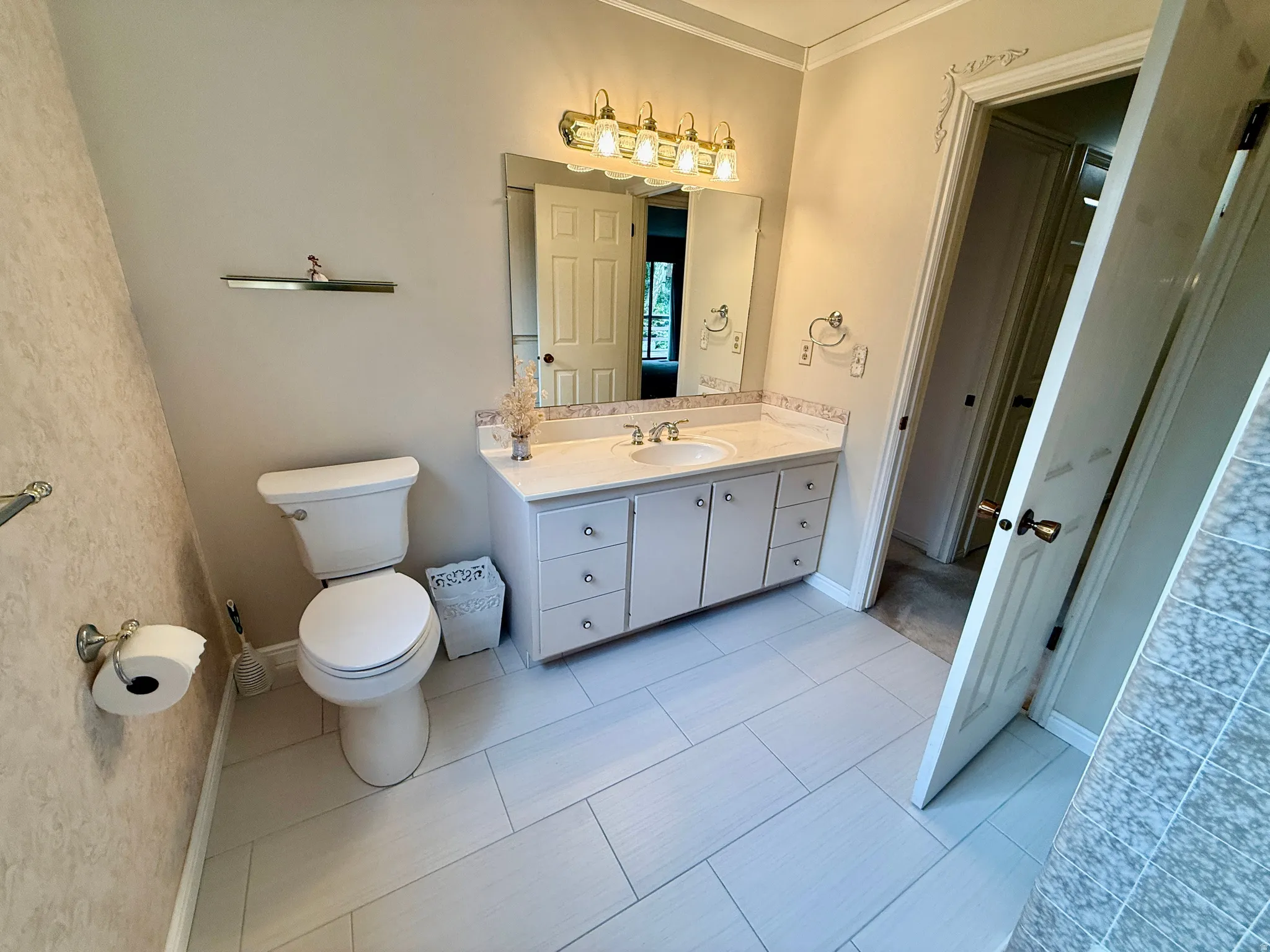 Bathroom 2 o main level- White vanity with integrated sink, decorative mirror, and brass-finish lighting fixture