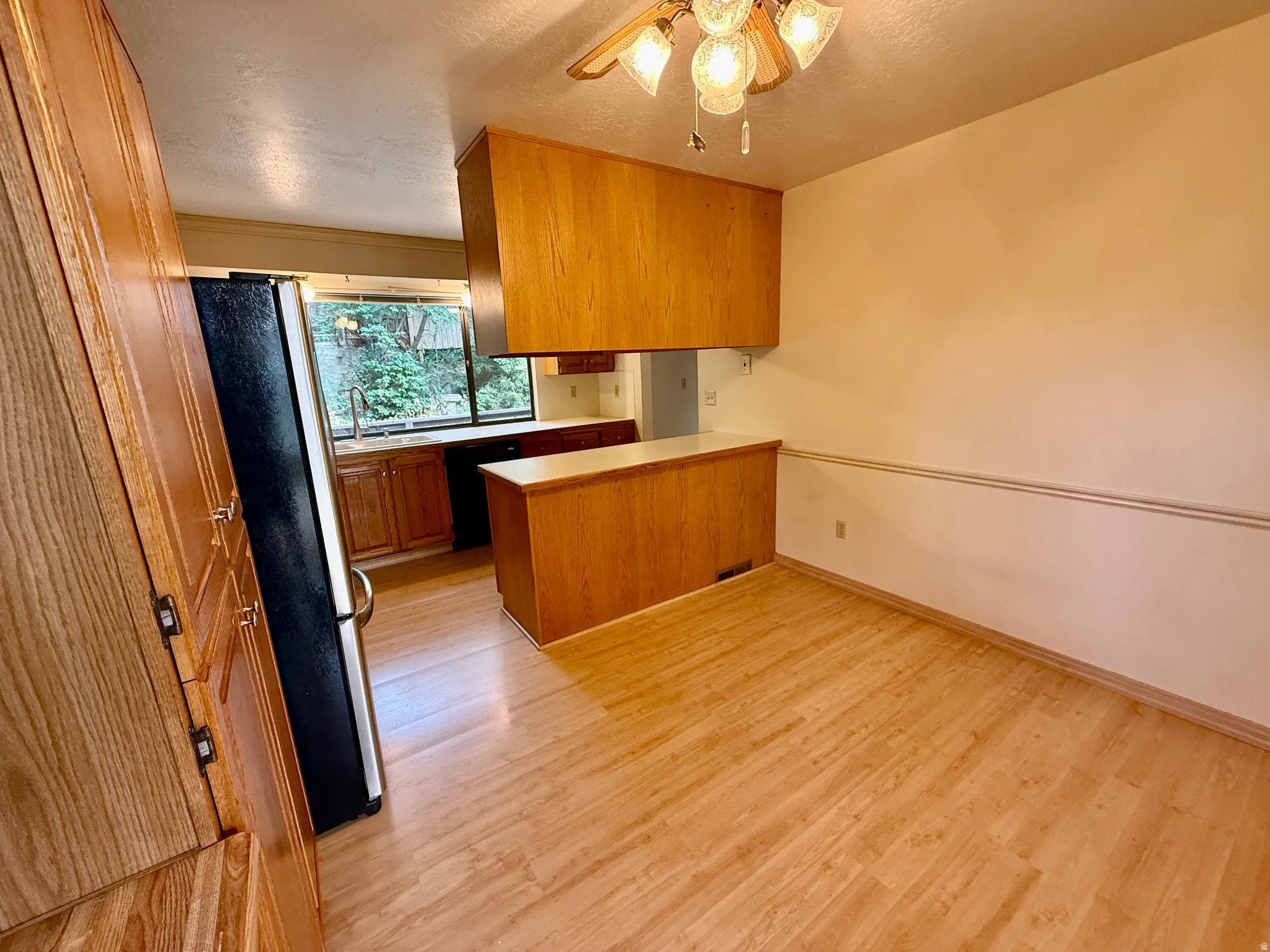 Kitchen and dining area featuring wood-finish flooring, wood cabinetry, built-in breakfast nook and a large passthrough window to the deck.
