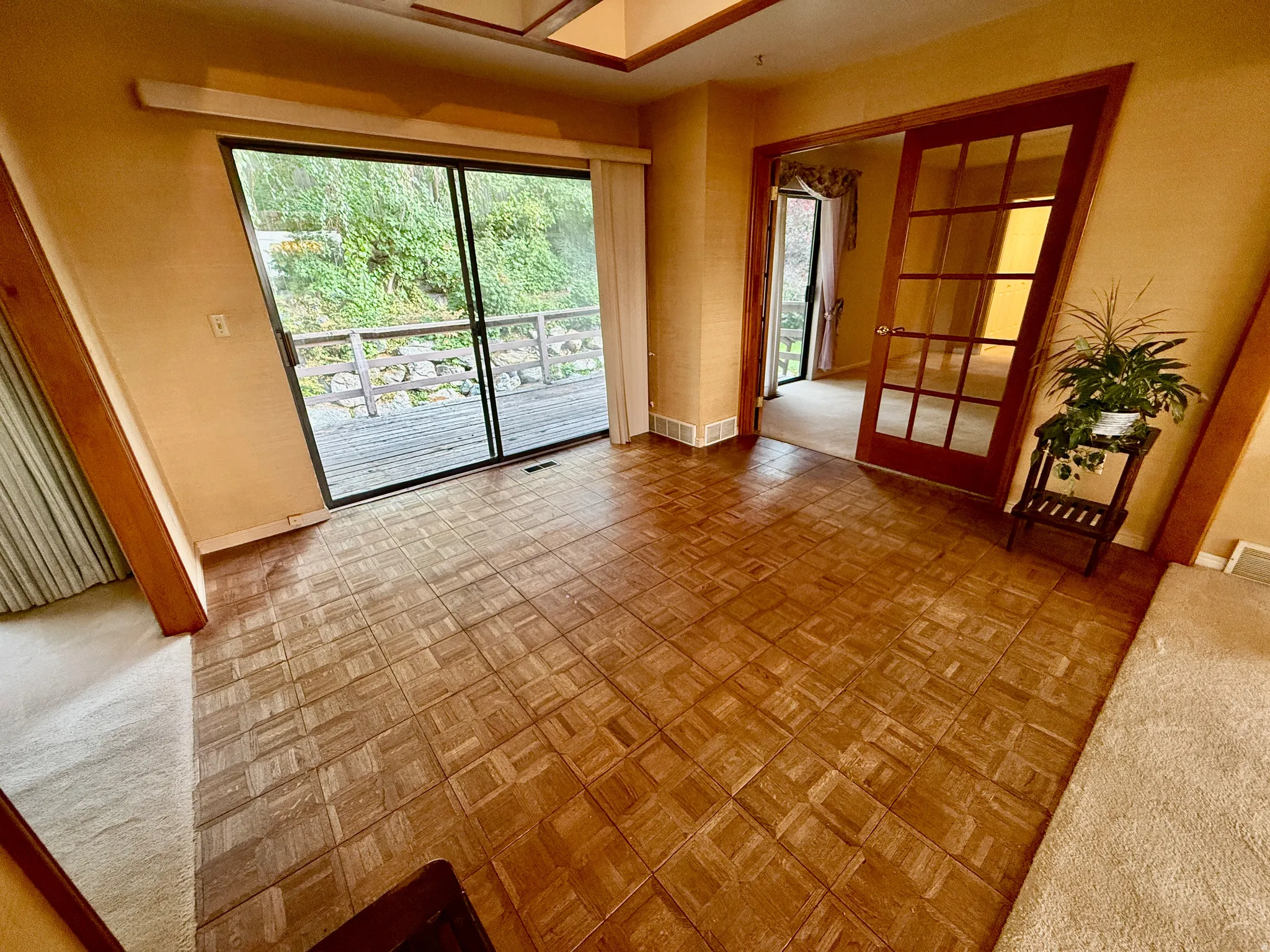 Wood-finish parquet flooring, sliding glass doors onto deck, skylight and French-style pocket doors