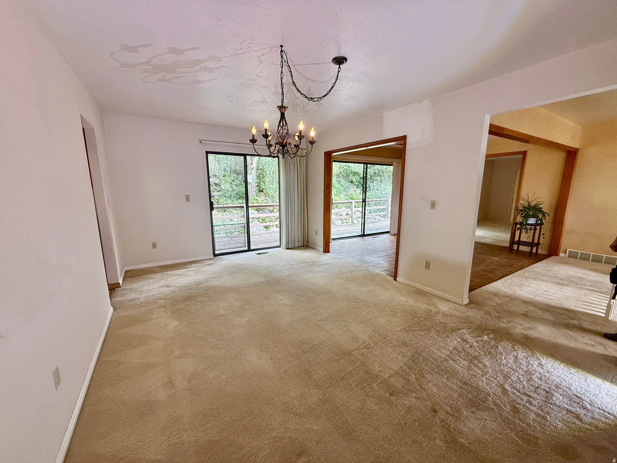 Sliding glass door access to an exterior deck, with a decorative chandelier illuminating the space