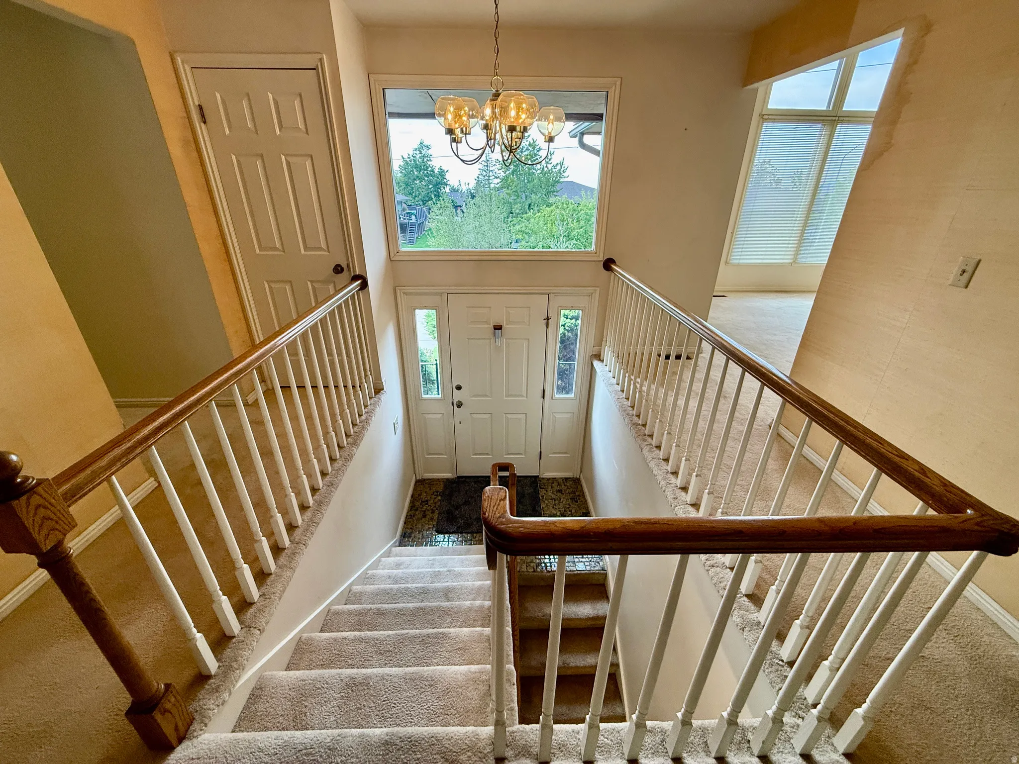 Two-story foyer with a transom window, sidelight windows, and a chandelier