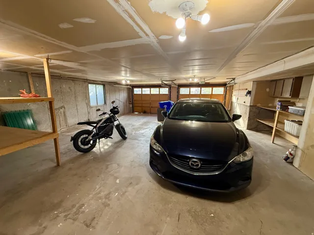 Attached garage featuring exposed concrete walls and ceiling-mounted lighting-extra wide and extra deep garage