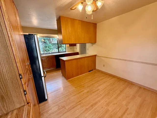 Kitchen and dining area featuring wood-finish flooring, wood cabinetry, built-in breakfast nook and a large passthrough window to the deck.