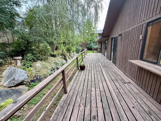 Expansive wood deck with a natural wood railing, vertical wood siding, and large windows