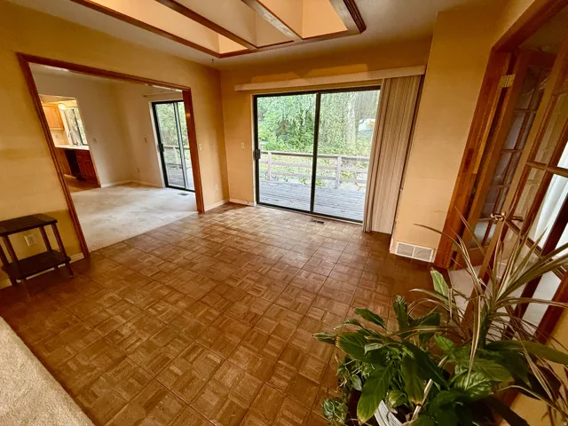 Wood-finish flooring, recessed Skylight with wood trim, sliding glass doors, deck access, and wood-frame French doors