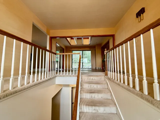 Bright upper-level hallway featuring white spindle railings, neutral finishes, and abundant natural light from multiple windows and skylights.