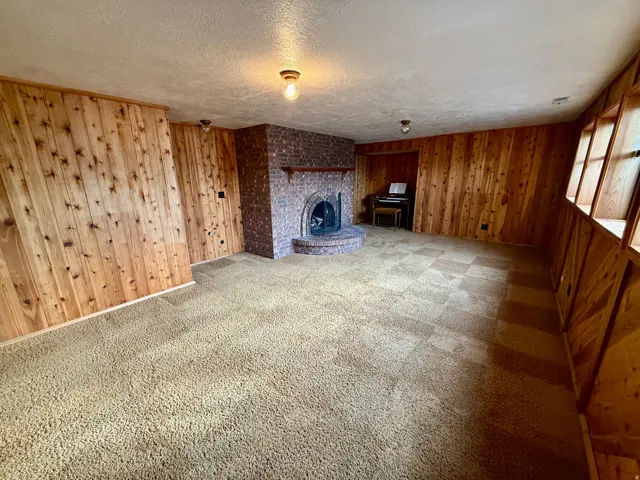 Brick fireplace with a raised hearth, wood paneling, and wall-mounted light fixtures