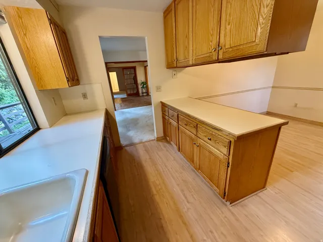 Kitchen with light wood-finish cabinetry, solid surface countertops, and an integrated sink