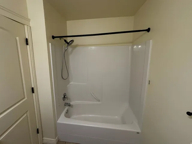White acrylic bathtub and shower combination with chrome fixtures