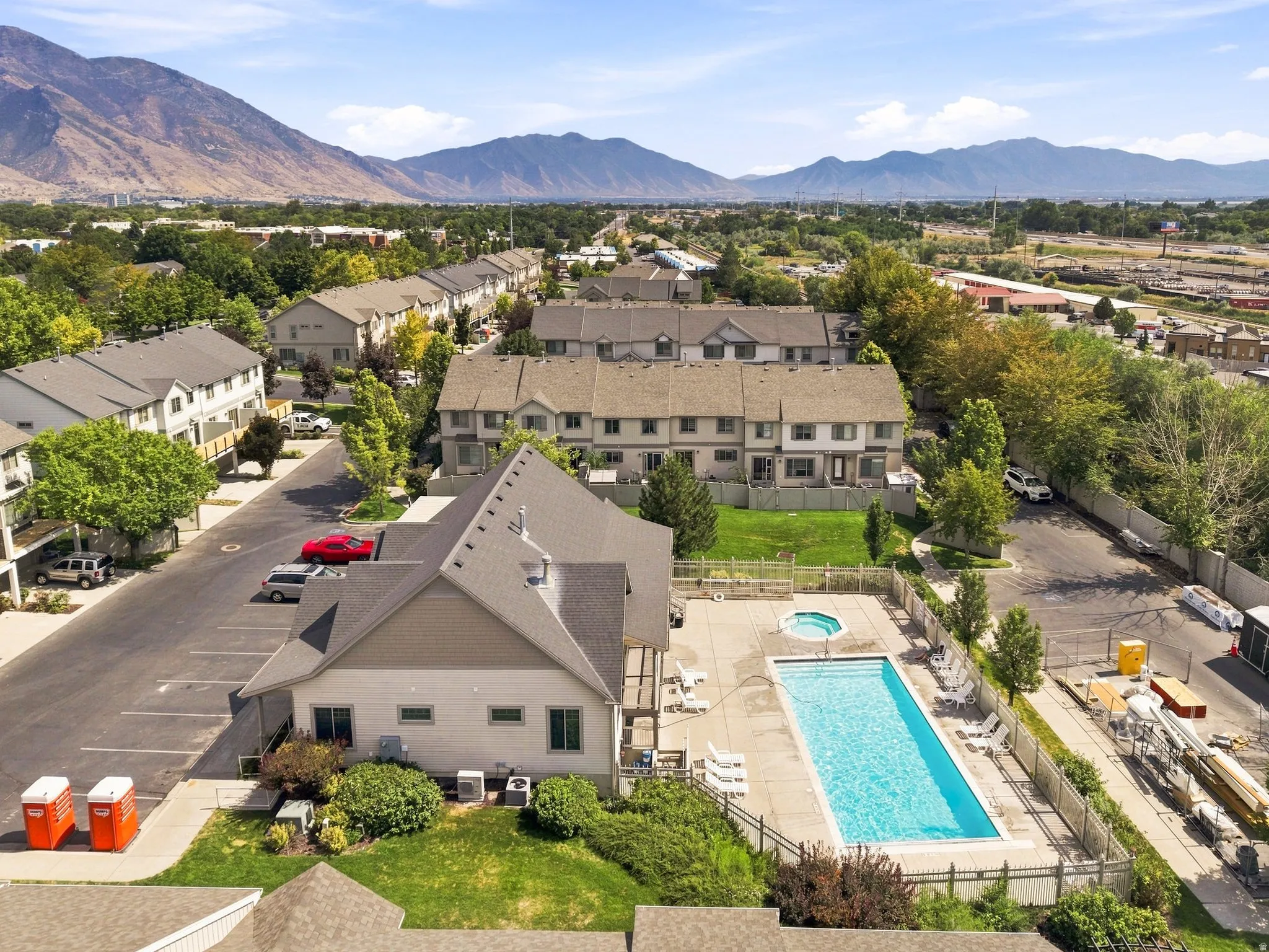 Community setting featuring multiple residential buildings, a central amenity building, and a swimming pool with a spa